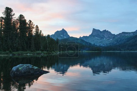 Zwei felsige Berggipfel spiegeln sich im Wasser des Sees bei sommerlichem Sonnenuntergang. Naturlandschaft