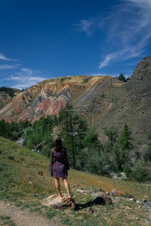 una joven con un vestido corto se levanta contra el telón de fondo del famoso hito Altai Mars en el cañón. concepto de viaje de verano