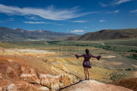 Concepto de viaje: Una mujer en un vestido corto está de pie con su espalda a la cámara, las manos que muestran la naturaleza grande y hermosa de la atracción turística Altai Mars, Kyzyl-Chin tracto. 