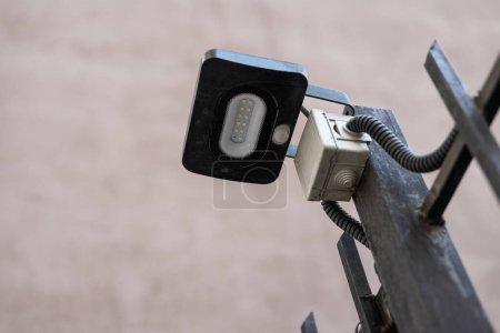 Photo for LED flashlight connected to residential building communications. Small Black street lamp with twelve diodes fixed to a metal fence outside. - Royalty Free Image