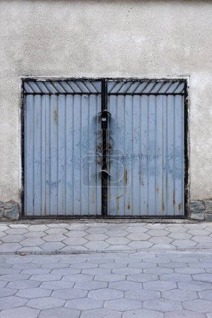 Antiguo garaje puertas de acero con cerradura en el patio. perfil metálico Plaza de aparcamiento puerta con óxido. 