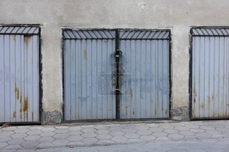 Old Car garage steel doors locked with a lock in the courtyard of an apartment building. metal profile Parking space gate with rust. 