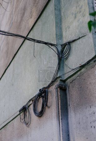 Stadtkommunikation: viele Drähte, die an der Hauswand befestigt sind. Stromleitung an ein Plattenhaus angeschlossen. 