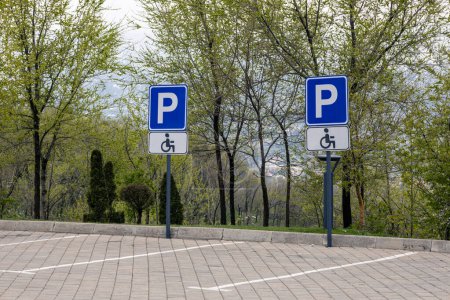 Foto de Dos señales de tráfico de estacionamiento para discapacitados fijadas en postes. Marcas de carreteras para plazas de aparcamiento en las adoquines - Imagen libre de derechos