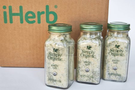 Téléchargez les photos : Trois bocaux de sel d'ail et d'herbes de marque Simply Organic, assaisonner les épices. Boîte en carton avec logo iHerb, achats en ligne. Acheter des produits dans une boutique en ligne. Bichkek, Kirghizistan - 8 déc. 2023 - en image libre de droit