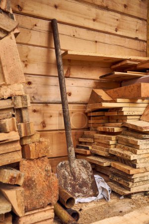 Baustelle eines Holzhauses, umweltfreundliche Materialien. Bretter und Balken, Schaufel an Wand gelehnt. Landarbeit, Sägewerk