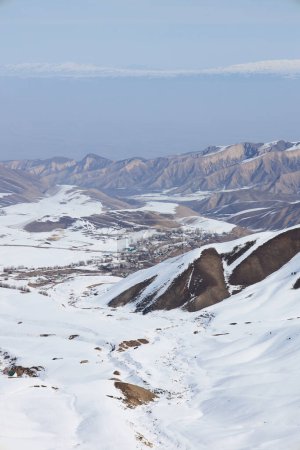 Village entre montagnes. Vallée de montagne enneigée le jour d'hiver. Pentes enneigées. La vie rurale près de la station de ski au Kirghizistan. Paysage naturel. Station de ski Toguz Bulak au Kirghizistan. 