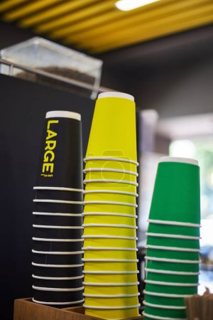 Foto de Tazas de papel de colores, negro grande, amarillo medio, verde taza pequeña de diferentes tamaños para bebidas calientes café, té para llevar. Mockup para cafetería, tienda, negocio de café. Copiar espacio de bebidas de fondo - Imagen libre de derechos