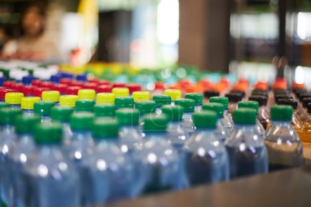 Lot of blue plastic half-liter small volume mineral water bottles, green yellow red cap in store, supermarket shelf, close up. High consumption plastic in everyday life, what pollutes the environment