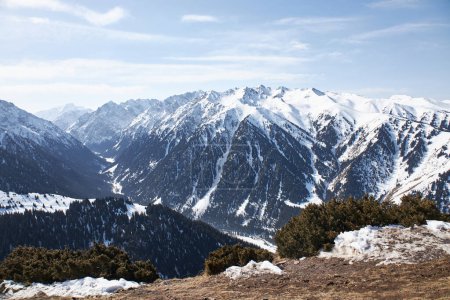 Winter natural landscape, mountain range. Amazing Panoramic view from top of slope on snow capped high mountains. Karakol Gorge, ski resort in Kyrgyzstan. 