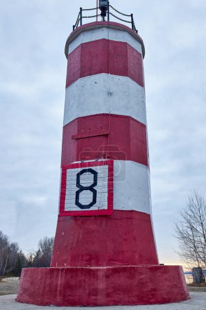 Small Lighthouse painted in red and white stripes with number eight 8. Building in Novosibirsk, Russian city, Siberia, Ob sea, river. Tourists destination. Travel around russia. Explore the country. 