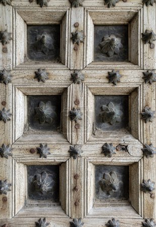 Fragment einer antiken alten Tür aus hellem, unlackiertem Holz und Metallmaterialien mit floralem Muster, Nahaufnahme. Elemente der Architektur alte Gebäude, Rollläden an den Fenstern