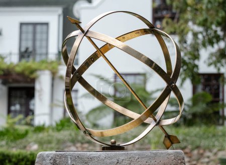 Large scale garden armillary sundial sphere with arrow and roman numerals. Hotel backyard