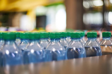 Blue plastic half liter small volume mineral water bottles with green cap in store, supermarket shelf, close up. High consumption of plastic in everyday life, what pollutes the environment