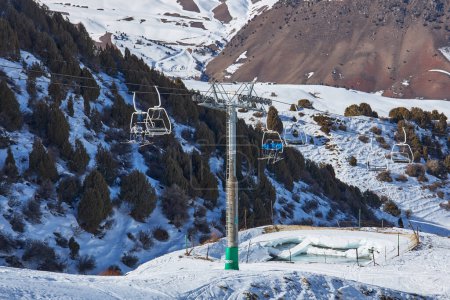 Photo for Skiers and snowboarders goes up on a ski lift, leading to the top of mountain slope. Ropeway pole, construction. Winter vacation activity, lifestyle. Resort Chunkurchak, Kyrgyzstan - 21 Feb 2023 - Royalty Free Image