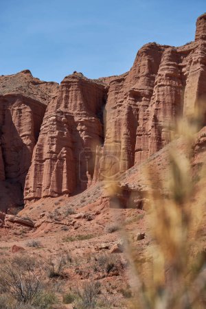 Sheer cliffs subject to erosion, red rocks of Konorchek canyon, travel destination, famous landmark Kyrgyzstan, Central Asia. Rock formation, natural landscape, hiking trekking area, sandstone