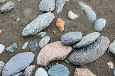Piedras de diferentes razas y colores se encuentran en la arena. gemología regional