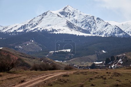 Majestuosa montaña triangular cubierta de nieve y Countryside Road. Montañas naturales paisaje. Pyramid hill. Naturaleza primaveral en Kirguistán
