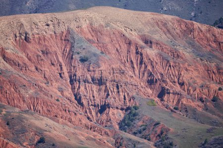 Terrain texturé motifs complexes teintes rouge foncé canyon rocheux. L'érosion naturelle a sculpté un paysage magnifique. La lumière et l'ombre accentuent les crevasses et les pics, merveille géologique de l'environnement aride
