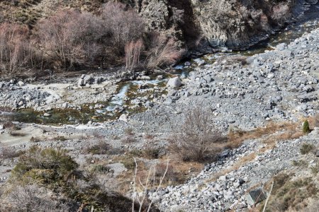 bends of small mountain river beautiful color with stones banks. Autumn natural landscape, top view. Branches of trees and bushes without leaves. Nature of Kyrgyzstan, Kyrgyz Republic in Central Asia