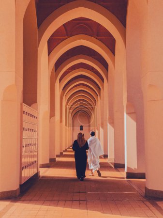 Photo for An unidentified Muslim pilgrim couple walk under symmetrical arches at Bir Ali mosque in Medina, Saudi Arabia. - Royalty Free Image