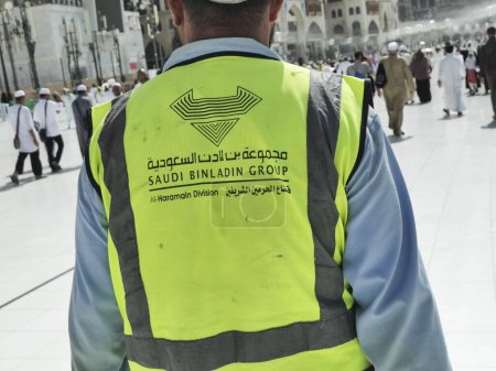 Téléchargez les photos : MECCA, ROYAUME D'ARABIE SAOUDITE-1 JUIN 2023 : Un homme non identifié porte une veste du Groupe Binladin saoudien à Makkah. Saudi Binladin Group est l'entrepreneur principal pour le projet d'expansion de Makkah. - en image libre de droit