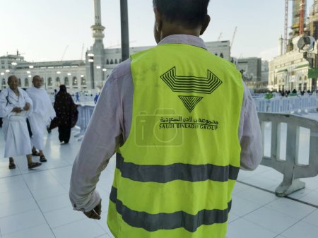 Téléchargez les photos : MECCA, ROYAUME D'ARABIE SAOUDITE-1 JUIN 2023 : Un homme non identifié porte une veste du Groupe Binladin saoudien à Makkah. Saudi Binladin Group est l'entrepreneur principal pour le projet d'expansion de Makkah. - en image libre de droit