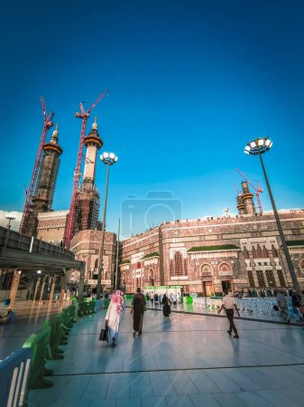 Photo for Unidentified people walk towards Al Haram mosque in Makkah, Saudi Arabia with blues skies in the background. The mosque is undergoing a heavy expansion project to accommodate more Muslim pilgrims. - Royalty Free Image