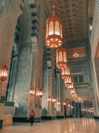 Photo for MECCA, KINGDOM OF SAUDI ARABIA-JUNE 4, 2023:An unidentified worker walks under chandeliers at the new King Abdullah extension in Makkah, Saudi Arabia. The new extension expected to cost USD30 billion. - Royalty Free Image