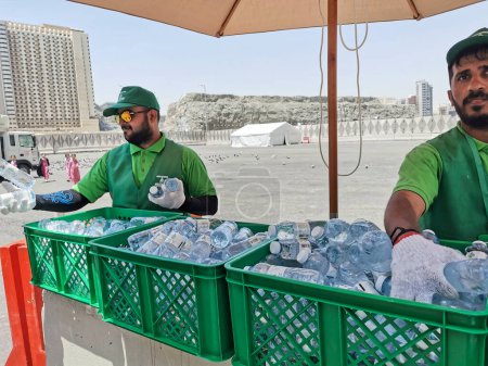 Photo for MECCA, KINGDOM OF SAUDI ARABIA-JUNE 4, 2023:Workers distribute cold drinks to Muslim hajj pilgrims. Due to hot weather during hajj season, pilgrims are advised to drink lots of water to stay hydrated. - Royalty Free Image