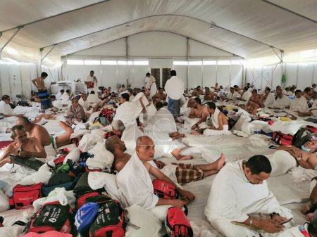Téléchargez les photos : 26 JUIN 2023-PLAINE D'ARAFAT, MINA, ARABIE SAOUDITE : Les pèlerins du hajj malaisien en vêtements blancs d'ihram se reposent après leur enregistrement dans la tente de la Plaine d'Arafat à Mina, La Mecque, Royaume d'Arabie Saoudite. - en image libre de droit