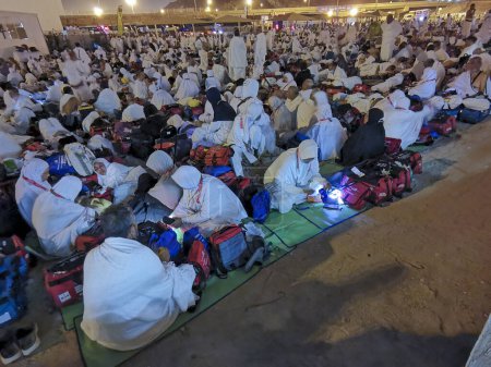 Téléchargez les photos : 27 JUIN 2023-MUZDALIFAH, MINA, ARABIE SAOUDITE : Des pèlerins du hajj de Malaisie en vêtements blancs d'ihram attendent leur bus à Muzdalifah, La Mecque, Royaume d'Arabie Saoudite. - en image libre de droit