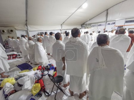 Photo for JUNE 26, 2023-PLAIN OF ARAFAT, MINA, SAUDI ARABIA : Malaysian hajj pilgrims in white ihram clothes get ready to pray (salah) inside the tent at Plain of Arafat in Mina, Mecca, Kingdom of Saudi Arabia. - Royalty Free Image