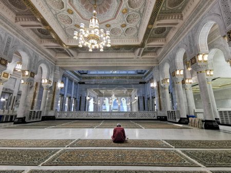 Photo for Unidentified Muslim man sits quietly inside a mosque. - Royalty Free Image