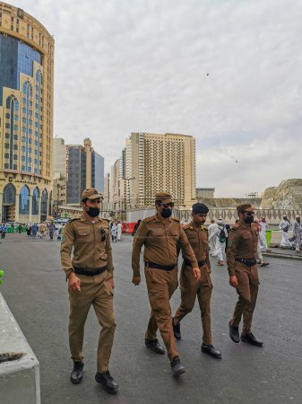 Photo for MAKKAH, KINDOM OF SAUDI ARABIA (KSA)-JULY 1, 2023 : A group of local policemen walk on to the Haram Mosque to resume their duties to watch over hajj pilgrims in Mecca, Saudi Arabia. - Royalty Free Image