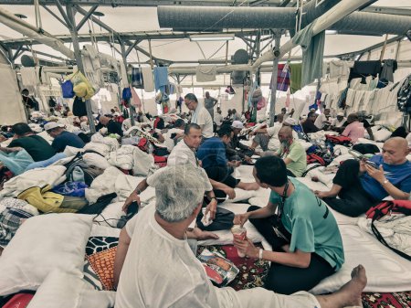 Téléchargez les photos : 29 JUIN 2023-PLAINE D'ARAFAT, MINA, ARABIE SAOUDITE : Les pèlerins du hajj malaisien en vêtements normaux se reposent dans la tente de Mina, La Mecque, Royaume d'Arabie Saoudite. - en image libre de droit
