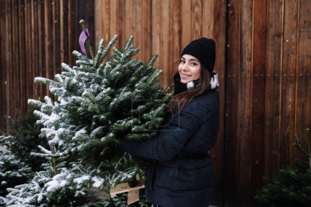 Foto de Hermosa mujer sostiene pequeño árbol de Navidad nevado - Imagen libre de derechos
