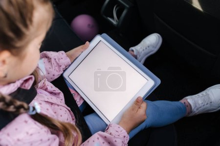 Photo for Mock up of little girl using digital tablet on car seat. Trip with family. High quality photo - Royalty Free Image