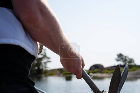 Foto de Man, wearing a life jacket, holding an anchor on a boat outdoors in the Swedish archipelago on a summer day. Photo taken in Sweden. - Imagen libre de derechos