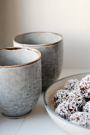 Téléchargez les photos : Two rustic coffee mugs and a plate with homemade raw chocolate balls, which is a classic no bake pastry in Sweden and Denmark. - en image libre de droit