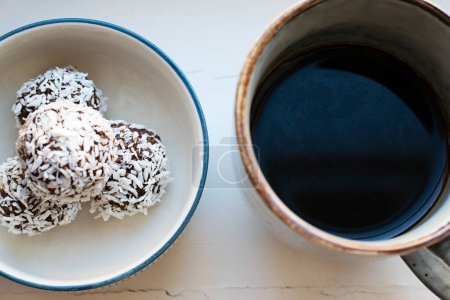 Foto de View from above of cup of black coffee and a plate with homemade raw chocolate balls, which is a classic no bake pastry in Sweden and Denmark. - Imagen libre de derechos