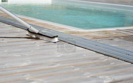 Foto de Cepillo de limpieza en la cubierta de madera junto a la piscina al aire libre en un día soleado de verano. Foto tomada en Suecia. - Imagen libre de derechos