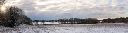 Foto de Vista panorámica del amanecer sobre el paisaje invernal con nieve en los campos y aguas tranquilas en el mar en el horizonte. Foto tomada temprano en la mañana en Karlskrona, Blekinge, Suecia - Imagen libre de derechos