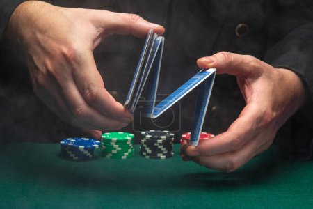 Photo for Dealer or croupier shuffles poker cards in a poker club against the background of a green table with chips. Concept of playing poker or gaming business. - Royalty Free Image