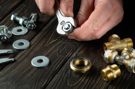 Foto de Tightening a nut with a wrench in the hands of a master. Installation or repair of gas equipment. - Imagen libre de derechos