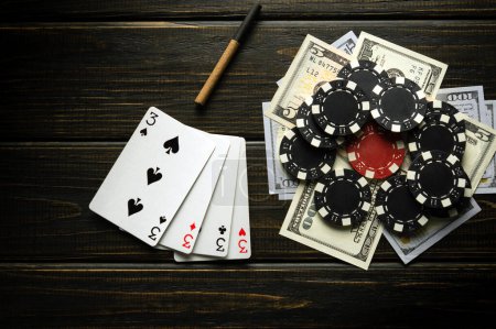 Foto de A poker game with a winning combination of four of a kind or quads. Cards with chips and money on a black table in a poker club. - Imagen libre de derechos