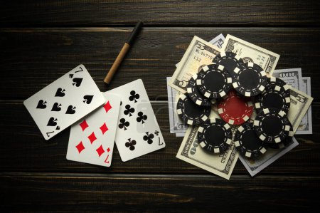 Photo for Playing cards with a winning combination of three of a kind or set and money with chips on a black vintage table. Winning in sports or poker depends on luck. - Royalty Free Image