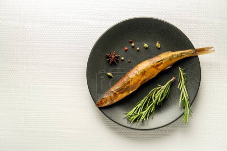 Photo for Smoked capelin on a dark plate with rosemary is served for lunch. Free space for the menu. - Royalty Free Image