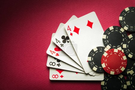 Foto de Jugar al póquer con una combinación ganadora de full house o full boat. Tarjetas con fichas en una mesa roja en un club de poker. - Imagen libre de derechos
