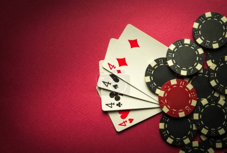 Foto de Juego de póquer con una combinación ganadora de cuatro de un tipo o quads. Tarjetas con fichas en una mesa roja en un club de poker - Imagen libre de derechos